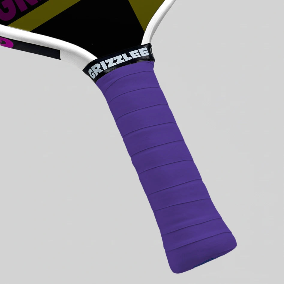 Close-up of a purple pickleball paddle grip with 'GRIZZLEE' branding on a gray background