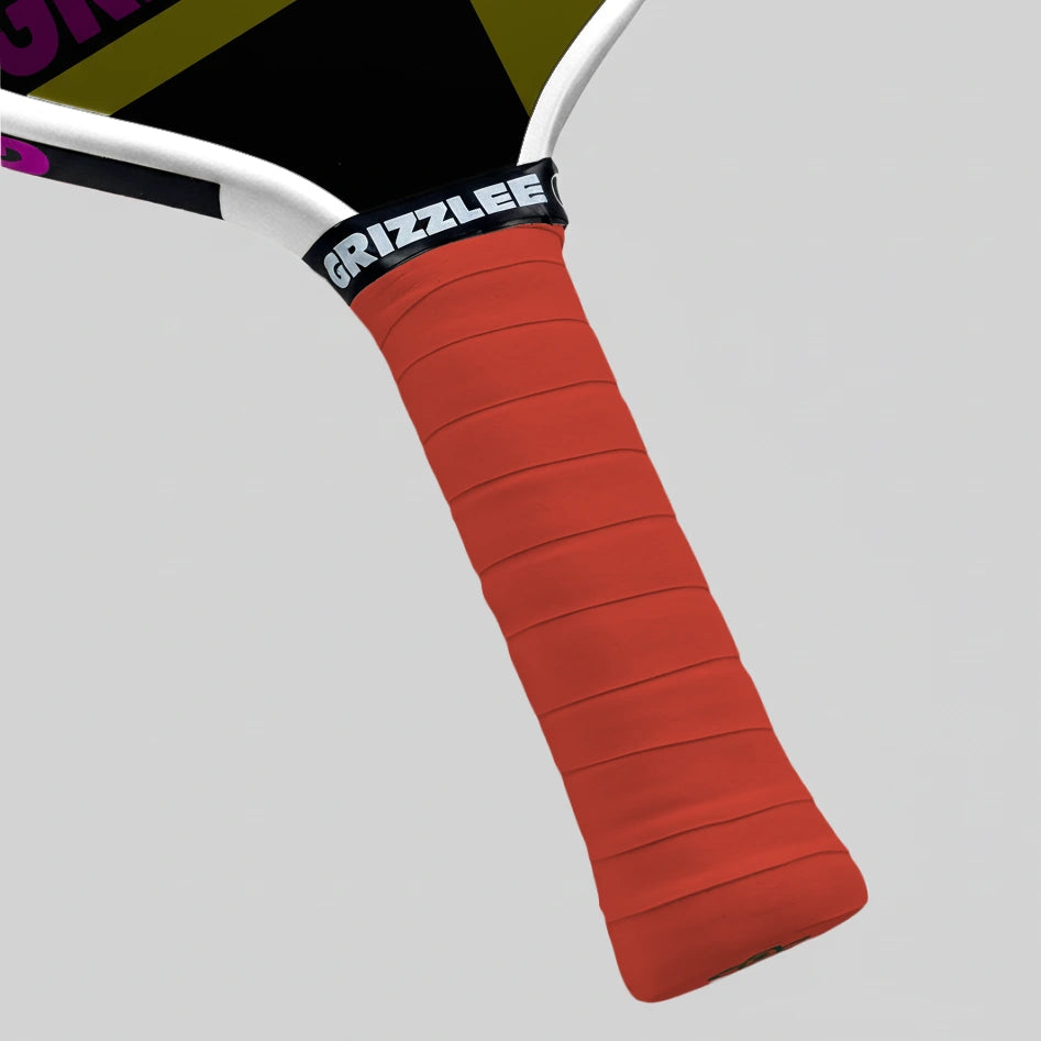 Close-up of a red pickleball paddle overgrip with 'Grizzlee Gripz' branding on a gray background
